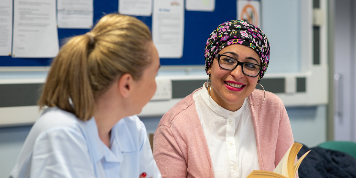 Professional development - Two ladies sat in an office smiling and talking to each other