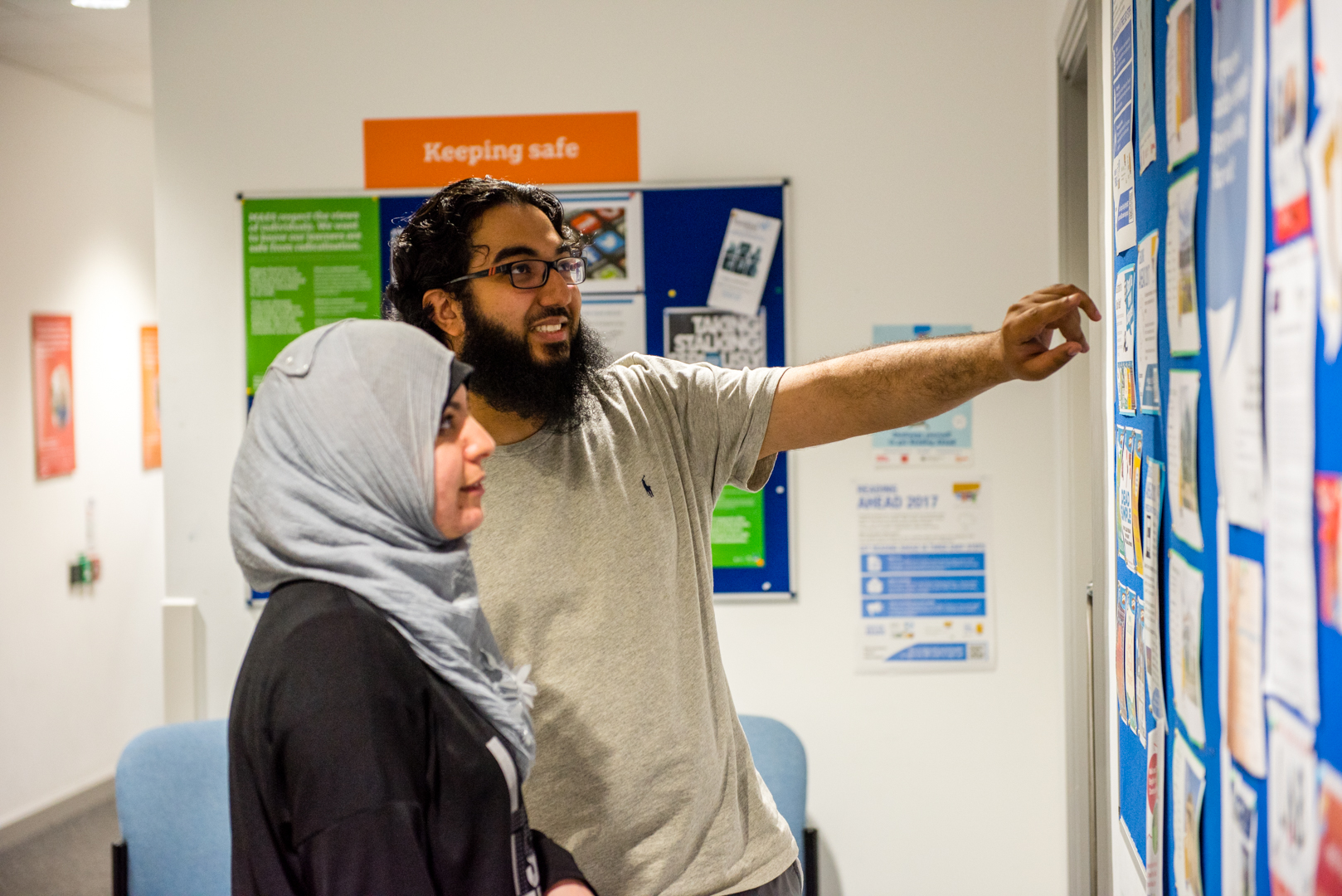 Two people pointing and looking at a noticeboard