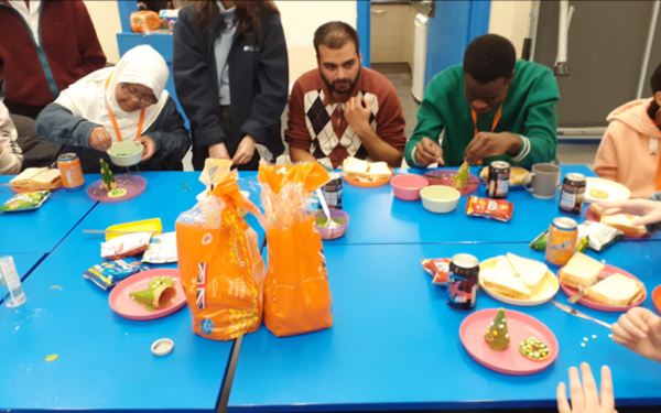 Group of people sat round a table eating and making sandwiches