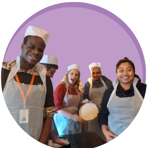 Group of people stood making pizzas on purple circle graphic background