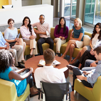 Large group of people all sat around a table in an office undertaking staff training