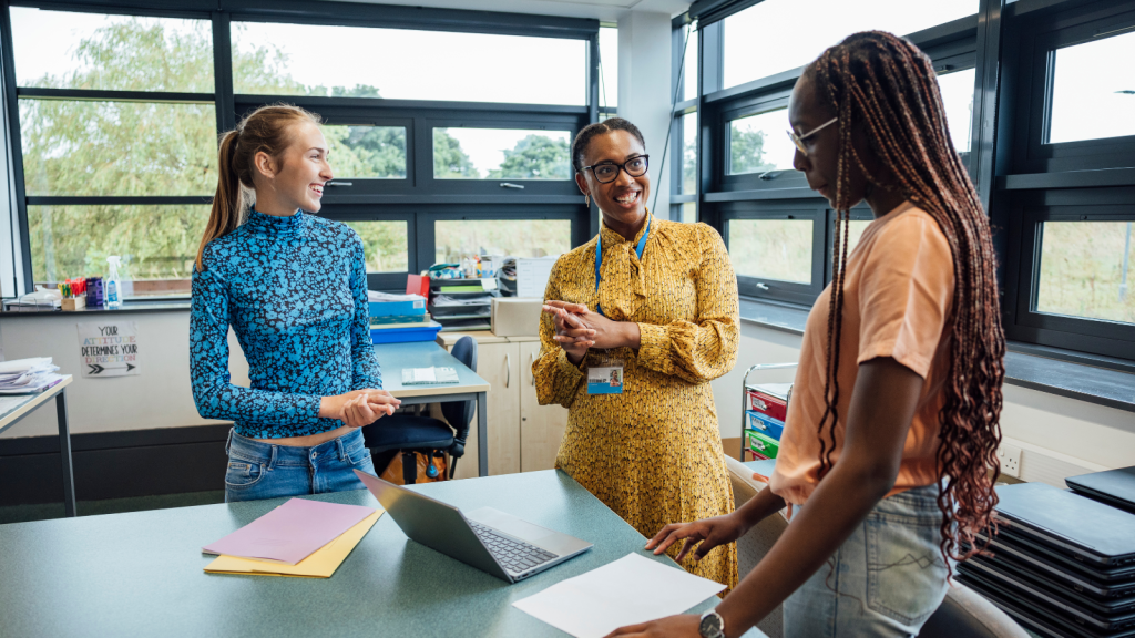 Teacher talking to two students in classroom