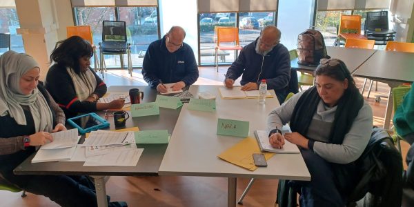 Group of people sat around a table completing a written task