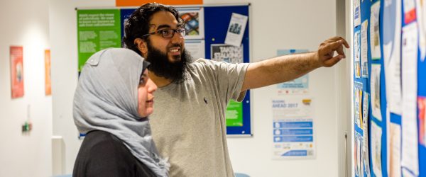 Two people pointing and looking at a noticeboard