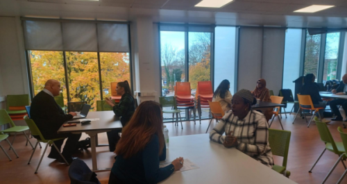 People sat in groups of two at tables in a classroom doing a mock interview