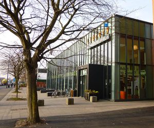 A modern glass building with orang lettering that reads 'Library'