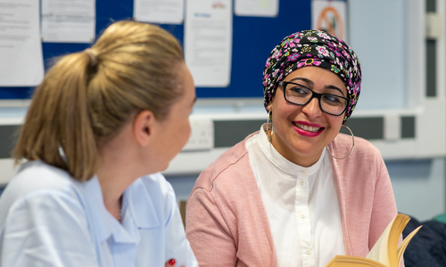 Professional development - Two ladies sat in an office smiling and talking to each other
