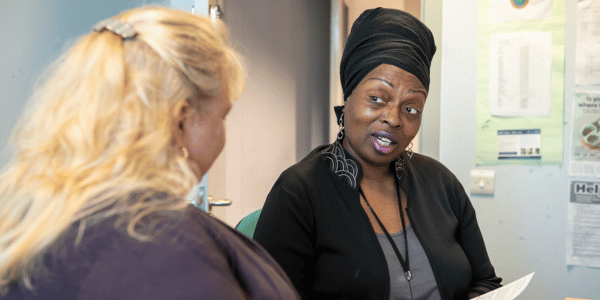 Two ladies sat in an office talking